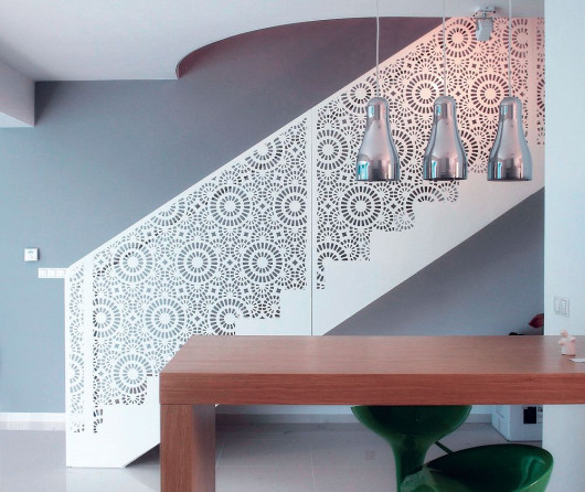 Wykonana na zamówienie według projektu indywidualnego balustrada z lakierowanej, ciętej laserowo stali tworzy na ścianie grę światła i cienia