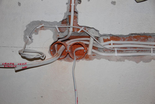 Podwójna puszka instalacyjna wyposażona we wkręty, osadzona w ścianie murowanej