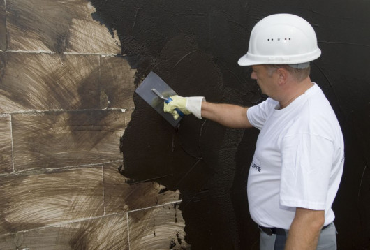 Nakładanie pierwszej warstwy grubowarstwowej izolacji bitumicznej (fot. Botament®)