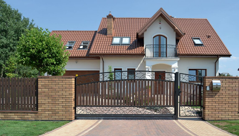 Wzory z kutej stali ozdabiają jednoskrzydłową przesuwną bramę i furtkę oraz balustradę na balkonie