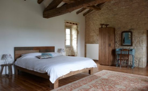 Drewniane meble w naturalnej barwie, wyeksponowane belki stropowe i ściany w kolorze ziemi nadają wnętrzom niepowtarzalnego uroku