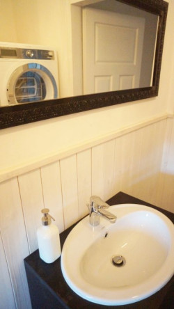 W dolnej łazience uroku dodały pomalowana na biało boazeria, kolorowy żyrandol i kinkiety