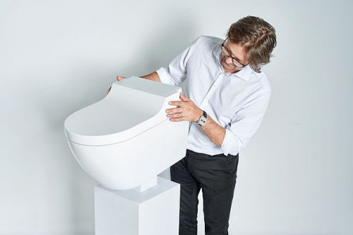 Renomowany projektant przemysłowy Christoph Behling z zaprojektowaną przez niego nową toaletą myjącą Geberit AquaClean Tuma