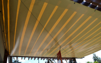 Taras zadaszony dwiema pergolami z kantówki sosnowej i pergotendą z plandeki samochodowej