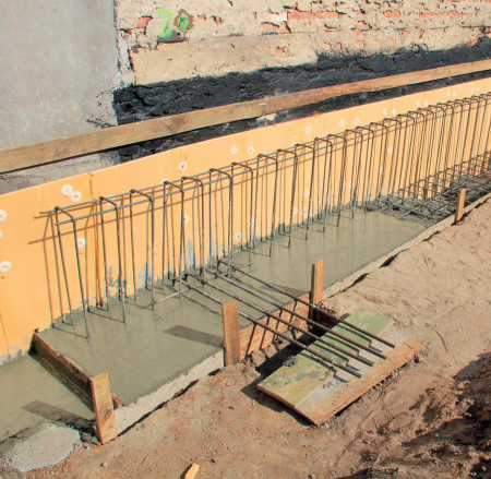 Zbrojenie ławy fundamentowej zalewane betonem. Widoczne startery pod ławy poprzeczne, prostopadłe do granicy działek.