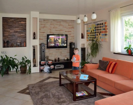 Ściany salonu dekorują obrazy oraz okładziny z drewna i piaskowca. 