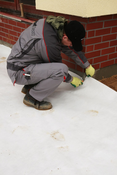 Budowanie tarasu: Układanie geowłókniny z wywinięciem kołnierza na ścianę budynku