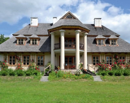 Dom stoi w najwyższym punkcie posiadłości, co dodatkowo podkreśla monumentalny sześciokątny ryzalit kolumnowy w centrum elewacji ogrodowej. Obejmuje taras i górny balkon, przylegający do sypialni właścicieli. Roztacza się z niego widok na tzw. salon ogrodowy, 2 stawy, groblę i Utratę