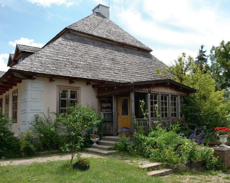 Przy zachodniej elewacji postawiono werandę z zewnętrznym wejściem do kuchni. Pod nią znajdują się drzwi do zachowanych piwnic. Kuchenną strefę budynku zwrócono, tak jak robiono to dawniej, w stronę zabudowań gospodarczych – stajni, kuźni. W tej części stoi również domek gościnny