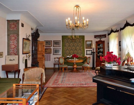 Salon, ulokowany w lewym skrzydle domu i wzdłuż elewacji ogrodowej, właściciele urządzili meblami i bibelotami odziedziczonymi po rodzinie oraz kupionymi na targach staroci. Posadzki wykończyli parkietem dębowym. Wnęki okien zaopatrzyli w łukowe glify, w celu wpuszczenia większej ilości światła