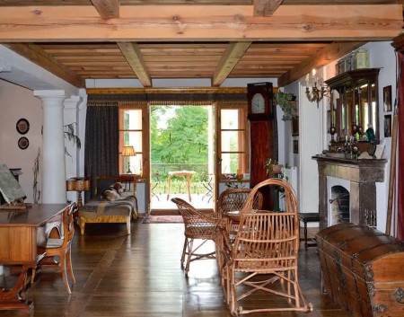 Sień ozdabia fałszywy strop z drewnianych bali, który skonstruowano pod stropem terriva. Taras i obudowę otwartego kominka wykonano z marmuru polskiego. Podłogę – z trepów schodów, które Waldek kupił w warszawskiej kamienicy, przeznaczonej do rozbiórki. Przy salonie widać pilastry i kolumny