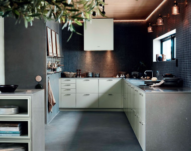 Neutralna zabudowa kuchenna Bistro tworzy wraz z surową kamienną mozaiką na ścianie i gładką betonową podłogą oryginalną loftową aranżację