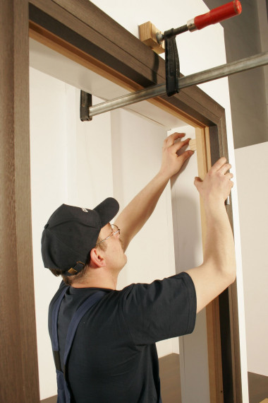 Obsadzaną ościeżnicę blokujemy za pomocą klinów, pilnując pionów