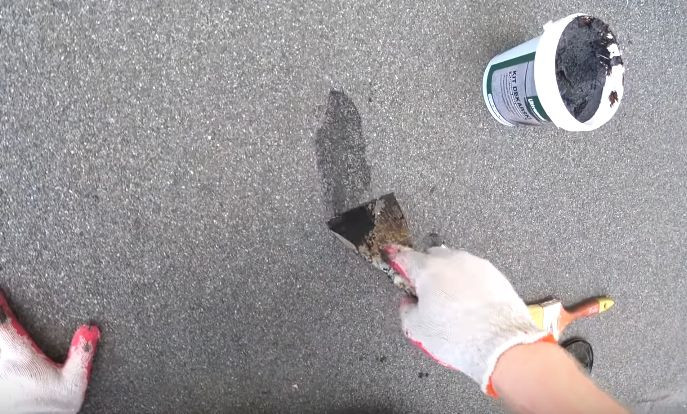 Renowacja pokrycia dachowego z papy pzred zimą - pęknięcia oczyszczamy, nakładamy kit, wyrównujemy i pozostawiamy do wyschnięcia