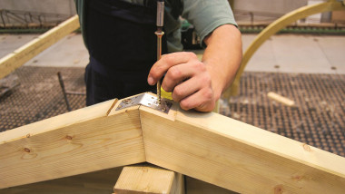 Budowa wiaty garażowej - na konstrukcji układa się krokwie, łącząc je na szczycie