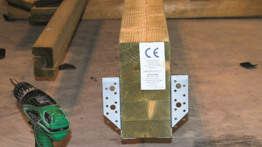 Budowa wiaty garażowej - kantówkę mocujemy na specjalne podstawy do konstrukcji