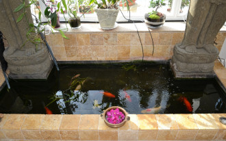 Murowany ogród zimowy z oczkiem wodnym w środku