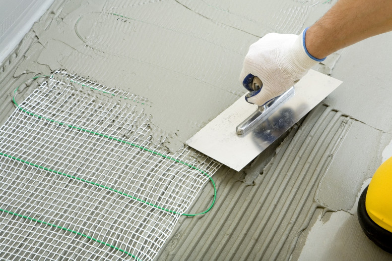 Umieszczanie maty grzejnej w warstwie kleju pod płytkami