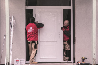 Pozycjonowanie skrzydła drzwi z ramą doświetli w otworze ściany budynku