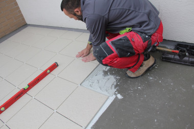 Płytkę dociska się i lekko porusza nią na boki, żeby klej szczelnie wypełnił przestrzeń pod okładziną.