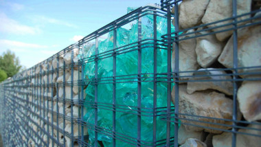 Ogrodzenie gabionowe wypełnione kamieniami i szkłem