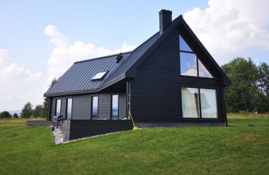 Nowoczesna bryła domu z bali, z dużymi przeszkleniami i pokryciem z blachy na rąbek