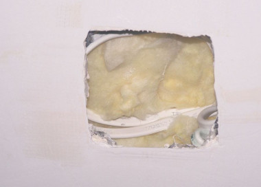 Dziura w płycie gipsowo-kartonowej i paroizolacji pozostawiona do zainstalowania oświetlenia