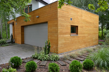 Oblicówkę z drewna na garażu ułożono poziomo, na wpust i pióro.