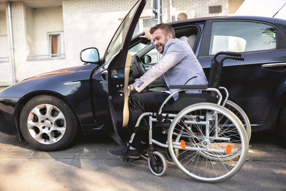 Osoba na wózku inwalidzkim wsiadająca do samochodu