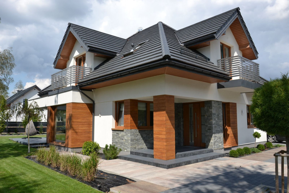 Elewacja wykończona tynkiem silikonowym, okładziną z granitu oraz płytami styropianu wytłoczonymi na wzór słojów drewna