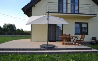 Taras z kostki betonowej zadaszony balkonem i parasolem