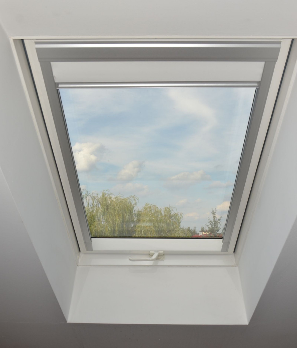 Okno dachowe ze zwiniętą roletą wewnętrzną