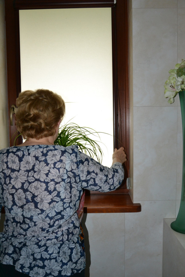 Właścicielka domu ręcznie steruje roletami wewnętrznymi