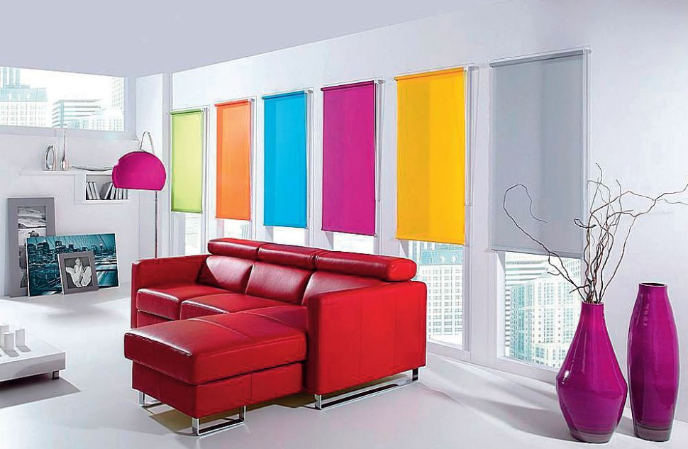 Czerwona sofa w salonie, na oknach kolorowe rolety