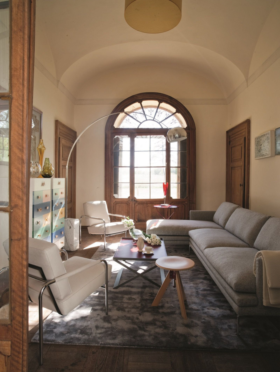 Wnętrze według marki Zanotta - sofa modułowa William w tkaninie, fotele Susanna w skórze, czerwony stolik Cumano oraz ikona designu, czyli stołek Giotto