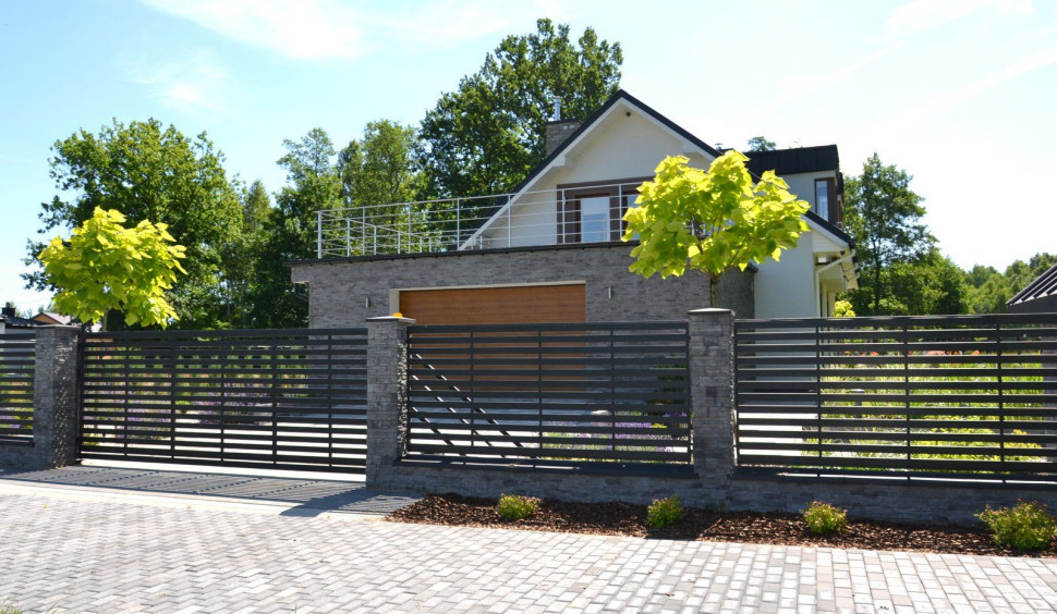 Ogrodzenie: Podmurówkę i słupki obłożono kamieniem elewacyjnym, a przęsła są ze stali zabezpieczonej proszkowo