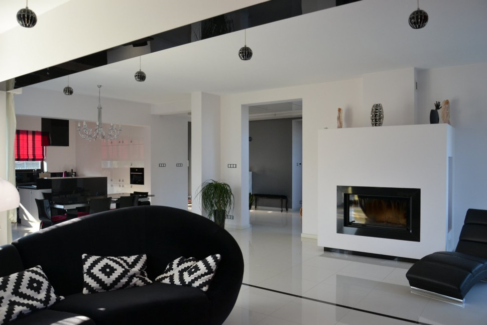 Salon z kominkiem łączy się z kuchnią i jadalnią