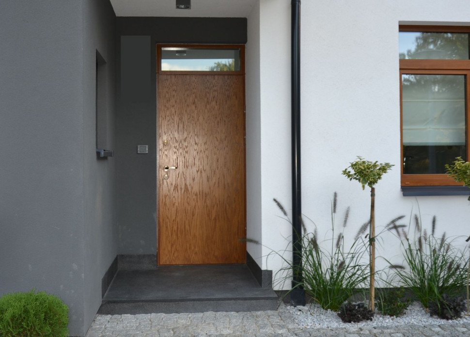 Stalowe drzwi zewnętrzne z górnym szklanym doświetlem są pokryte laminatem