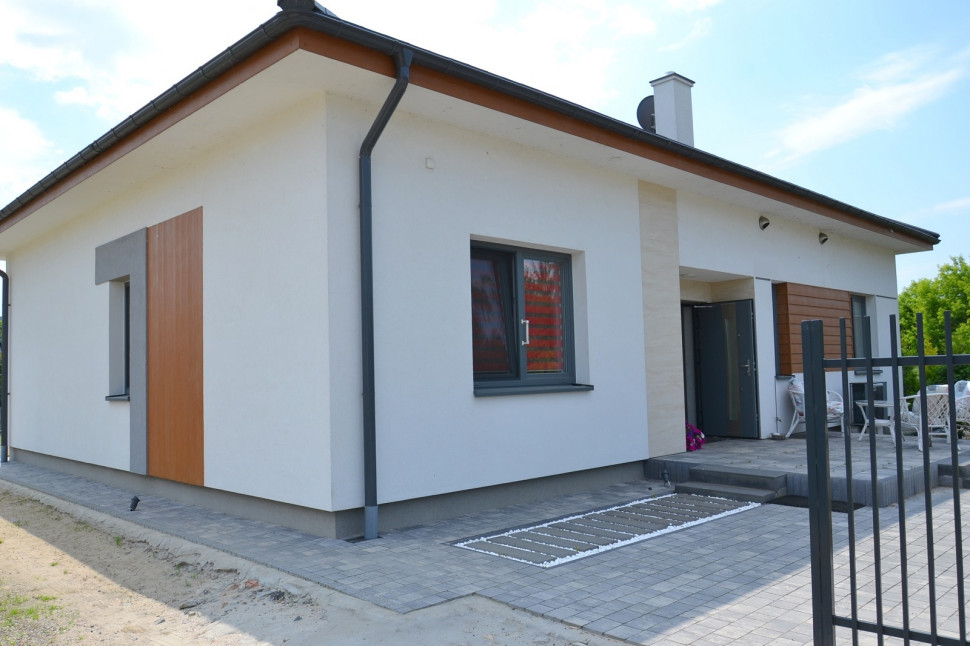Parterowy dom ma prostą bryłę i kopertowy dach o nachyleniu 25°, który właściciele przykryli angobowaną ceramiczną dachówką