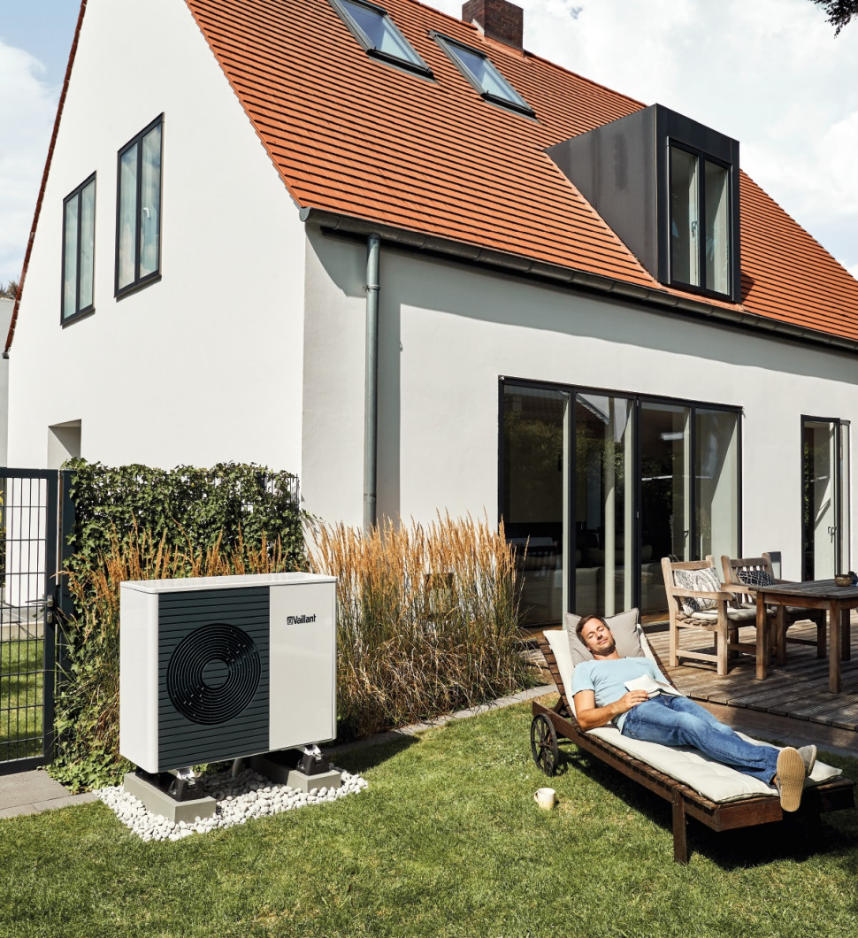 Mężczyzna wypoczywający obok zewnętrznej jednostki pompy ciepła Vaillant