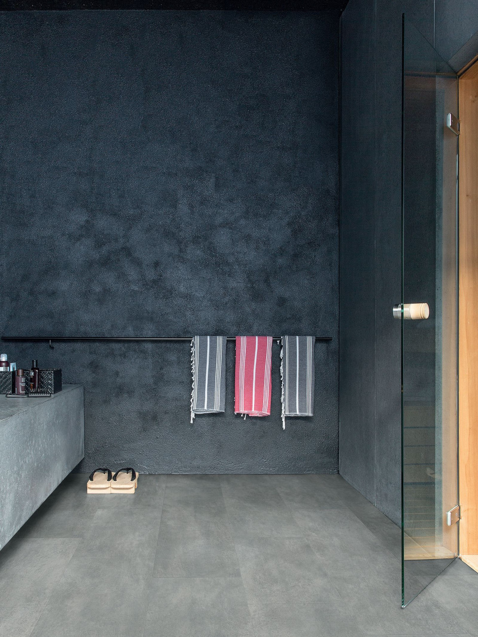 Łazienka według zen: surowe betonowe ściany pomalowane odporną na wilgoć grafitową farbą i wodoodporna winylowa podłoga Ambient Glue Plus o wzorze ciemnoszarego betonu, z paneli o wymiarach 32,7 x 130,5 cm, łączonych systemem Uniclic Multifit