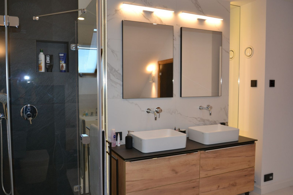 Na blacie umieszczono dwie umywalki, nad nimi podtynkowe baterie