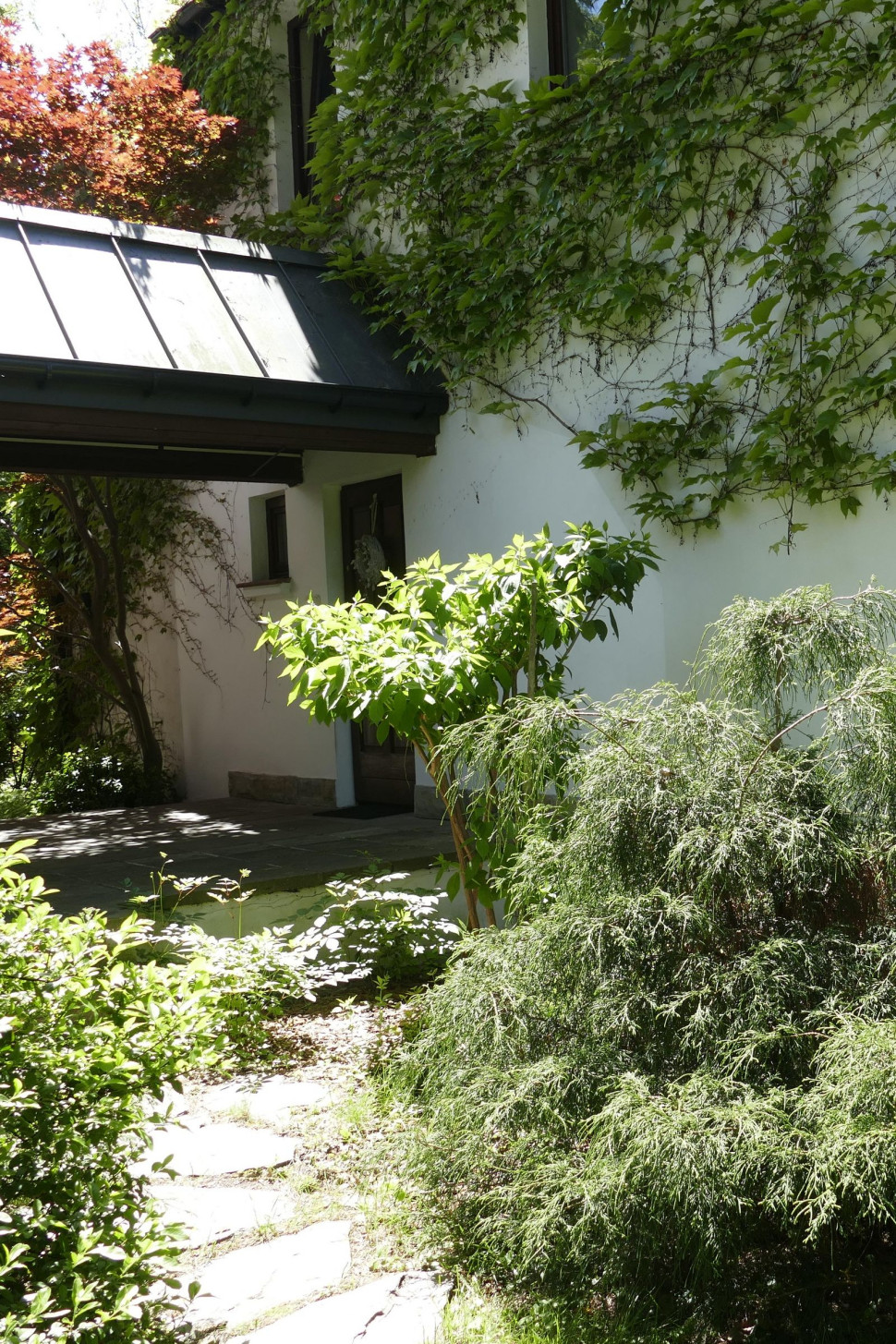 Główne wejście znajduje się pod daszkiem, łączącym budynek mieszkalny z garażem