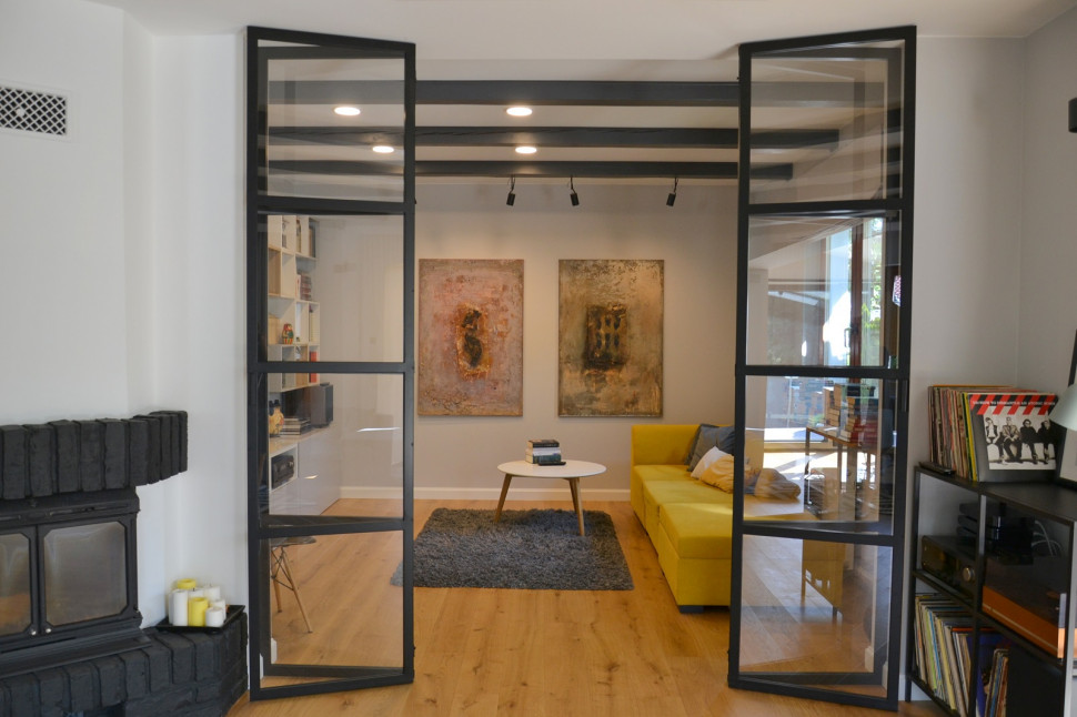 Lekkie przeszklenie w stylu loft, z metalu i szkła, oddzielające salon i pokój TV
