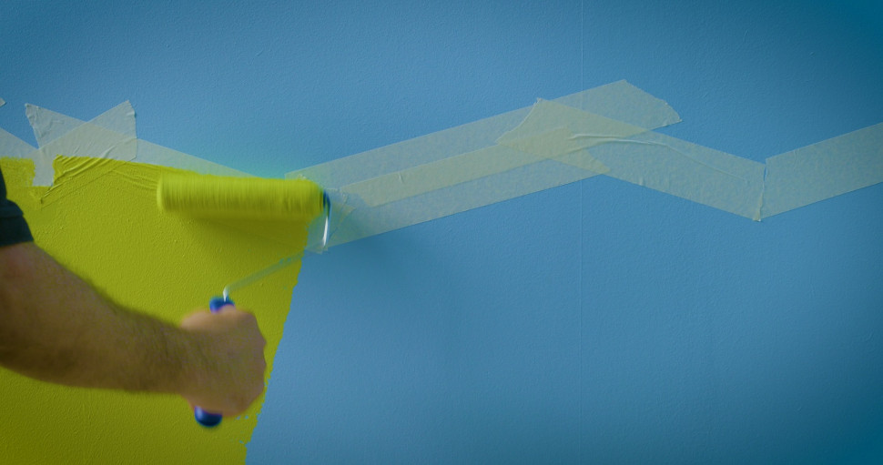 Kolorowe trolle w pokoju dziecka - krok 2) W dolnej części fragmentu ściany przyklejamy taśmę malarską, wyznaczającą kontur rozwianej, bujnej trawy