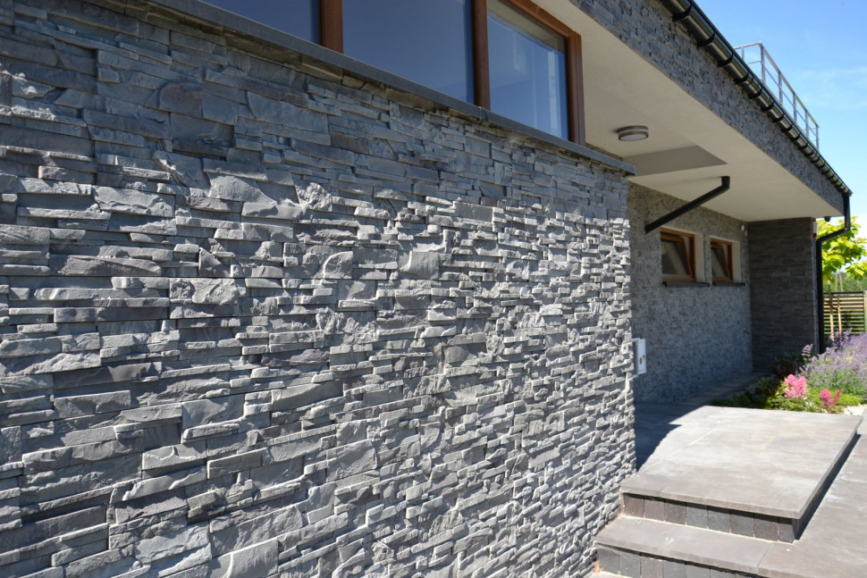 Ściana z kamieniem elewacyjnym i schody z płytami włoskiego trawertynu, w głębi - podtynkowe rynny