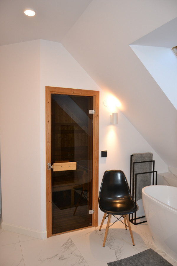 Szklane drzwi do sauny w łazience na poddaszu