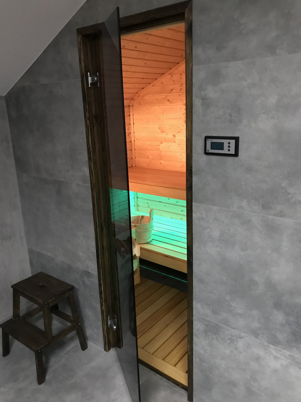 Szklane drzwi do sauny i regulator na ścianie
