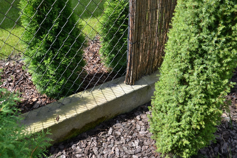 Elementy bocznego ogrodzenia: betonowy liniowy fundament, ocynkowana siatka i mata z wikliny