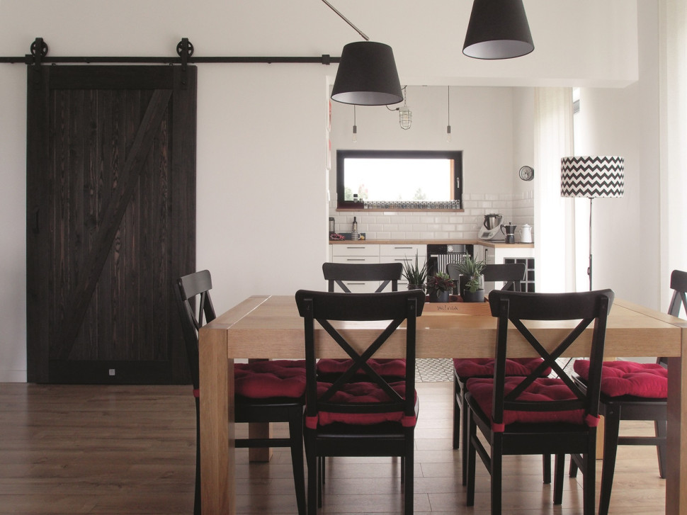 Mocnym akcentem stylizacyjnym w strefie wspólnej są przesuwne podwieszane drzwi z litego drewna w kolorze wenge (zamykają wiatrołap)